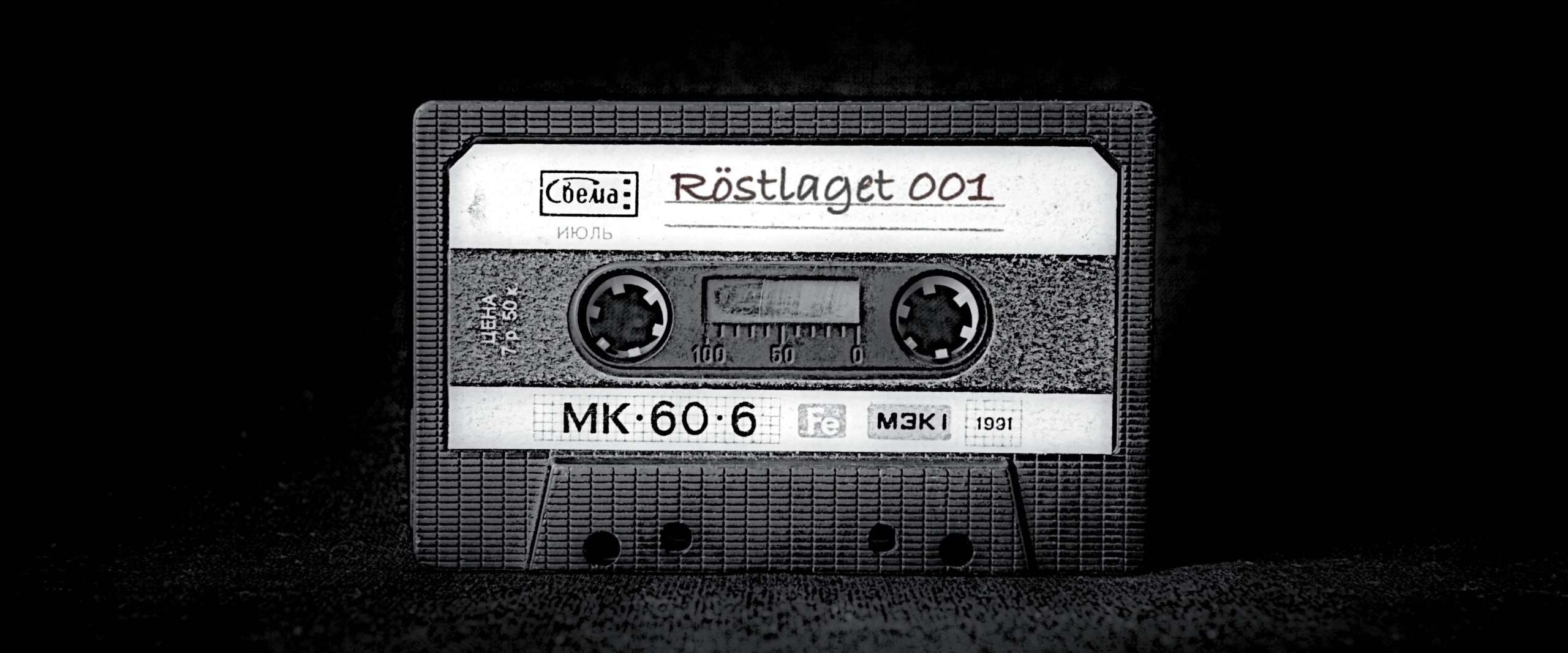 Ett svart kassettband står på mörk yta. Det står Röstlaget 001 på den ljusa etiketten.